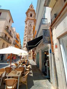 une rue avec des tables et des parasols et une tour d'horloge dans l'établissement Hotel El Siglo, à Valence