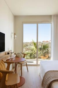 ein Schlafzimmer mit einem Bett, einem Tisch und einem großen Fenster in der Unterkunft Pátio do Tijolo in Lissabon