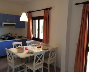 una cocina con una mesa blanca con sillas y una ventana en KAMARINA RESORT, en Scoglitti