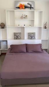 Un dormitorio con una cama morada con estanterías blancas en Jorsen House Tahiti 2 : bungalow confortable, en Taravao