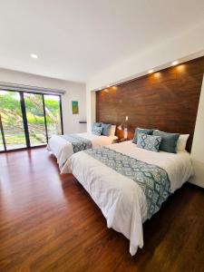 duas camas num quarto de hotel com pisos de madeira em Burbi Lake Lodge Monteverde em Monteverde