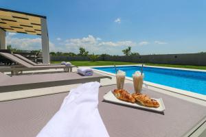 dos bebidas en una mesa junto a una piscina en Villa Gemini en Zadar