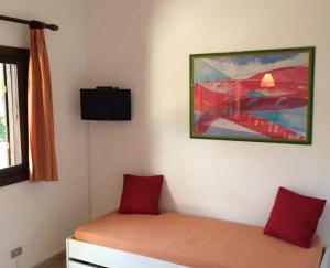 Un dormitorio con una cama con almohadas rojas y una pintura en KAMARINA RESORT, en Scoglitti