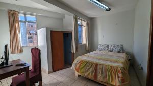 a bedroom with a bed and a desk and a window at Hospedaje Arequipa in Ayacucho