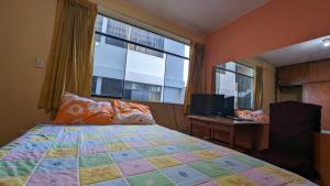 Schlafzimmer mit einem Bett, einem Schreibtisch und einem Fenster in der Unterkunft Hospedaje Arequipa in Ayacucho