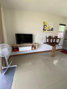 a living room with a tv and a table at Jorsen House Tahiti 2 : bungalow confortable in Taravao