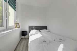 a white bed in a white room with a window at Dom & House - Apartments Old Town Dobra in Gdańsk