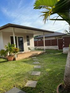 Cette maison dispose d'une terrasse et d'une pelouse. dans l'établissement Jorsen House Tahiti 2 : bungalow confortable, à Taravao