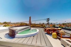a wooden deck with a table and chairs on a roof at Seaside Serenity Retreat Inviting condo in Oceanside with rooftop, hot tub, balcony, and ocean views in Oceanside