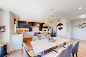a kitchen and dining room with a white table and chairs at Seaside Serenity Retreat Inviting condo in Oceanside with rooftop, hot tub, balcony, and ocean views in Oceanside