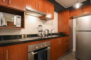 una cocina con armarios de madera y electrodomésticos de acero inoxidable en Art Deco 1BR with Pool View in Barranco, en Lima