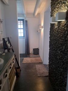 baño con lavabo y pasillo con alfombras en Casa Baleia Laranja Ocean-Front, en Cabeço Chão