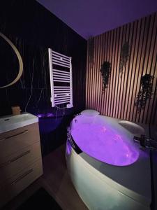 d'une salle de bains pourpre pourvue d'une baignoire avec un éclairage violet. dans l'établissement T4 jolie vue avec jaccuzzi, à Vitrolles