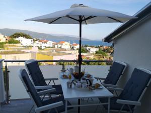 a white table and chairs with an umbrella on a balcony at Apartman The View Krk in Krk