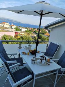 a white table with chairs and an umbrella on a balcony at Apartman The View Krk in Krk