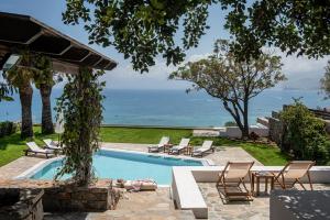 een zwembad met stoelen en uitzicht op de oceaan bij Villa Sunrise Majestic Seaview with Private Pool in Chersonissos