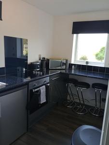 a kitchen with black counter tops and bar stools at Station Retreat in Boldon