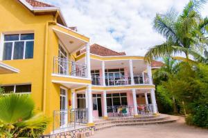 Casa amarilla con balcón y palmera en DANA KIGALI HOTEL en Kigali