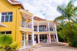 a yellow house with a balcony and a palm tree at DANA KIGALI HOTEL in Kigali