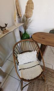 a rattan chair sitting next to a table with a vase at BUREAUX Appartements LESPARRE MEDOC in Lesparre-Médoc