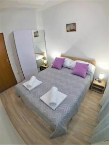 1 dormitorio con cama con almohadas moradas y espejo en Apartman Tina, en Ražanac