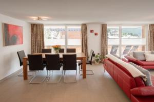 a living room with a table and a red couch at Haus Powder Snow in Zermatt