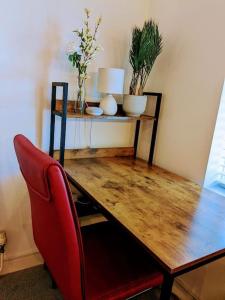una mesa de madera con una silla roja y una mesa con plantas en Stylish & Comfortable House in Swansea, en Morriston