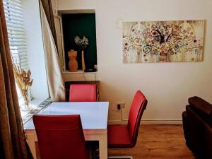 un comedor con sillas rojas y una mesa blanca en Stylish & Comfortable House in Swansea, en Morriston
