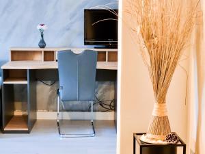 escritorio con silla y jarrón con hierba en Da Vinci Appartement, en Kapfenberg