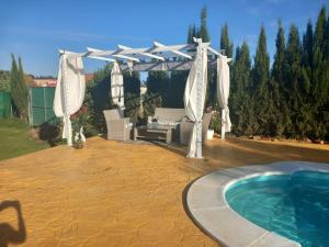 a backyard with a pool and a white pergola and a swimming pool at Casa Villa El Olivar in Huelva