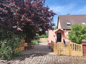 a house with a wooden fence and a tree at Storchennest mit großem Garten für Urlaubsgäste in Nauen