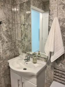 La salle de bains est pourvue d'un lavabo blanc et d'un miroir. dans l'établissement Lovely 1 Bed, Northolt Station, à Northolt