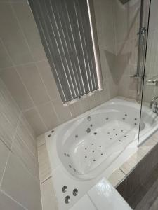 Luxury Apartment with a jacuzzi في ولفرهامبتون: حوض استحمام أبيض في حمام مع نافذة