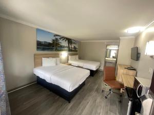a hotel room with two beds and a television at Days Inn by Wyndham Slidell in Slidell