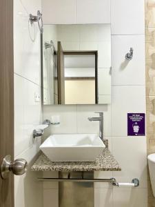 HOTEL VIOLETTA Cereté في Cereté: حمام مع حوض أبيض ومرآة