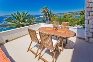 a wooden table and chairs on a balcony with the ocean at Villa Porthos in Hvar