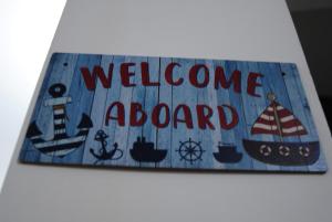ein Willkommensbrett mit Booten und ein Willkommensschild an Bord in der Unterkunft Casa Cinisi - Casa Vacanze in Cinisi
