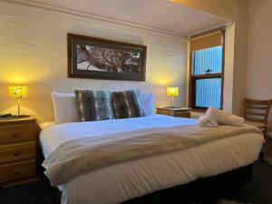 a bedroom with a large white bed with two lamps at Snow Gums 16, alpine-getaways in Dinner Plain