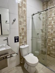 uma casa de banho com um WC e uma cabina de duche em vidro. em HOTEL VIOLETTA Cereté em Cereté