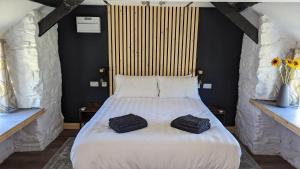a bedroom with a large white bed with two bags on it at Romantic Hideaway in Trawsfynydd