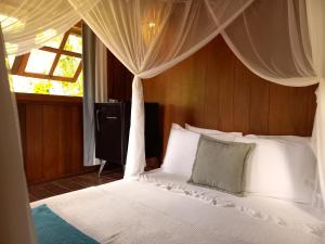 a bedroom with a white bed with a canopy at Bangalôs da Aldeia Caraiva in Caraíva +38 photos
