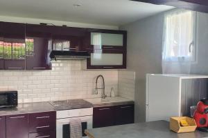uma cozinha com armários castanhos e um frigorífico branco em Tulsa Home - Appartement 2 chambres, Charmant et moderne avec terrasse privée em Osny