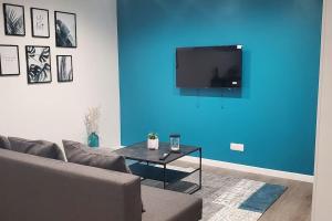uma sala de estar com um sofá e uma parede azul em Tulsa Home - Appartement 2 chambres, Charmant et moderne avec terrasse privée em Osny