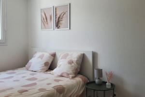 a bedroom with a bed with two pillows and a table at Tulsa Home - Appartement 2 chambres, Charmant et moderne avec terrasse privée in Osny
