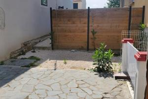 a garden with a fence and a wooden gate at Tulsa Home - Appartement 2 chambres, Charmant et moderne avec terrasse privée in Osny
