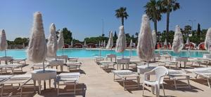a pool with chairs and umbrellas in front of a resort at Le tre sirene in Porto Cesareo
