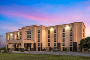 Best Western Plus Jonesboro Inn & Suites في جونزبورو: مبنى الفندق مع غروب الشمس في الخلفية