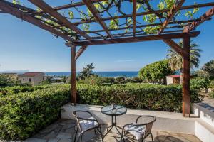 eine Terrasse mit einem Tisch, Stühlen und Meerblick in der Unterkunft Little Seaside Villa in Hersonissos in Hersonissos