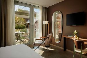 a hotel room with a bed and a desk and a window at NH Collection Heidelberg in Heidelberg