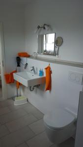 ein Badezimmer mit einem Waschbecken, einem WC und einem Spiegel in der Unterkunft BeHappy in Rust